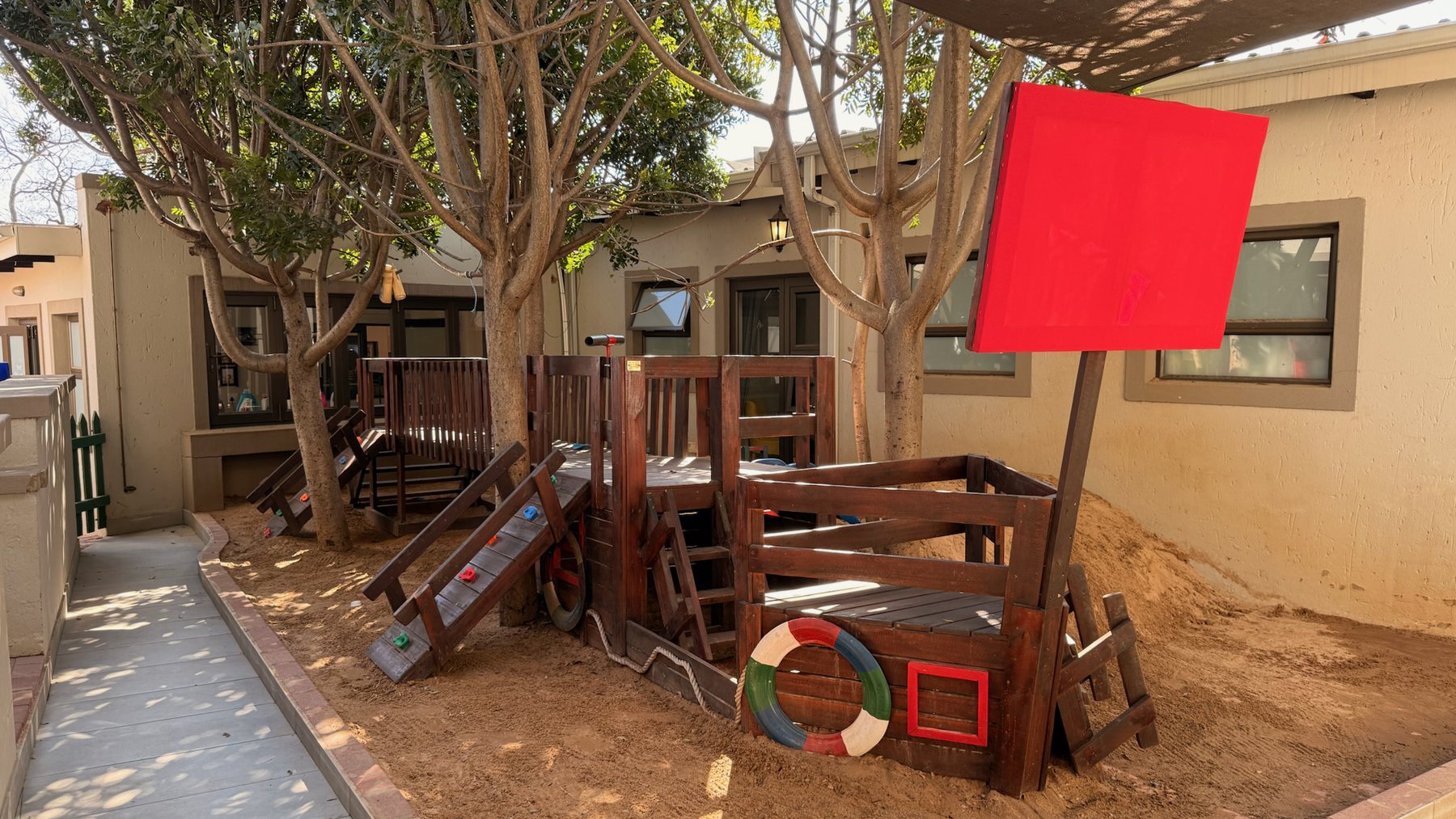 Die houtklimraam met sy rooi seil onder die bome by Greenhill